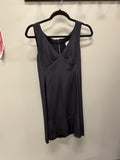A sleeveless black dress with a V-neckline and gathered front detail, hanging on a black hanger against a plain beige wall.