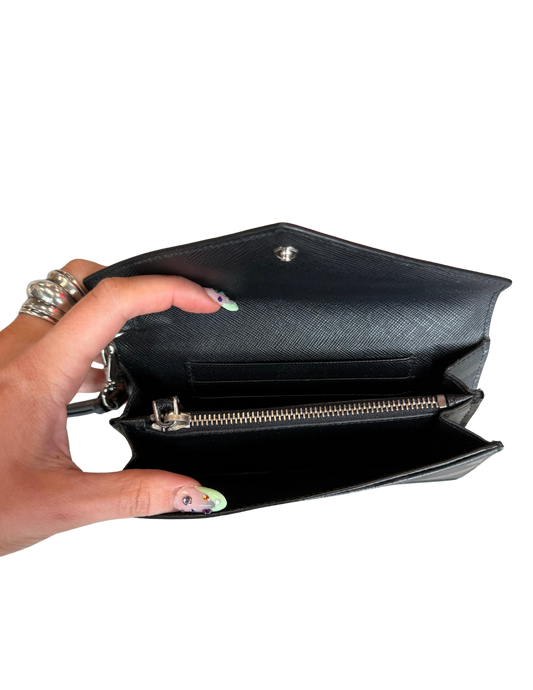 Hand holding a black clutch bag with a white background