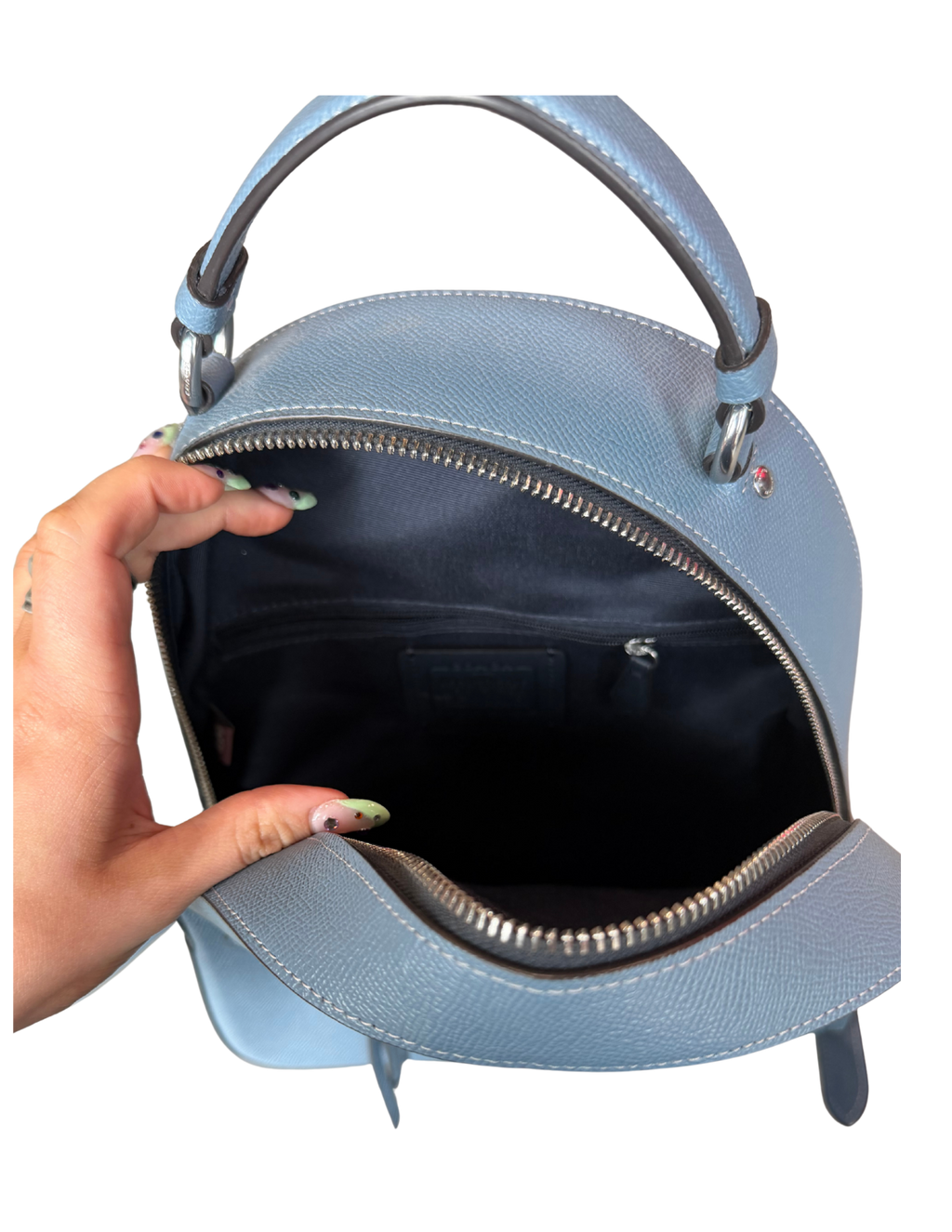 Light blue handbag with a hand holding it open on a white background