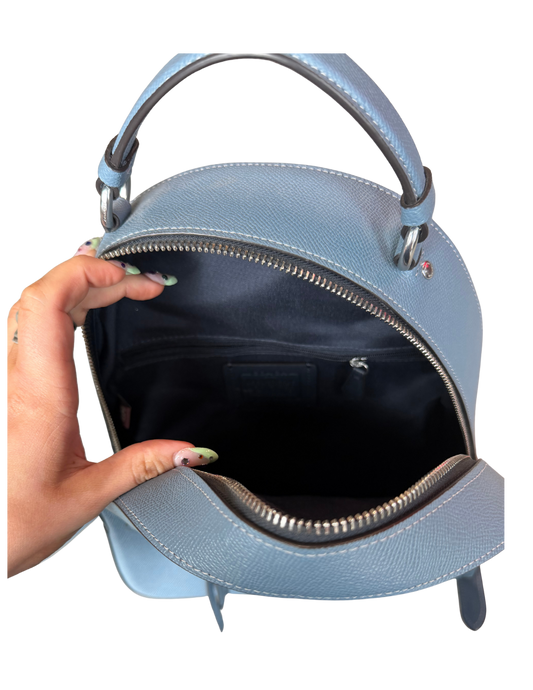 Light blue handbag with a hand holding it open on a white background